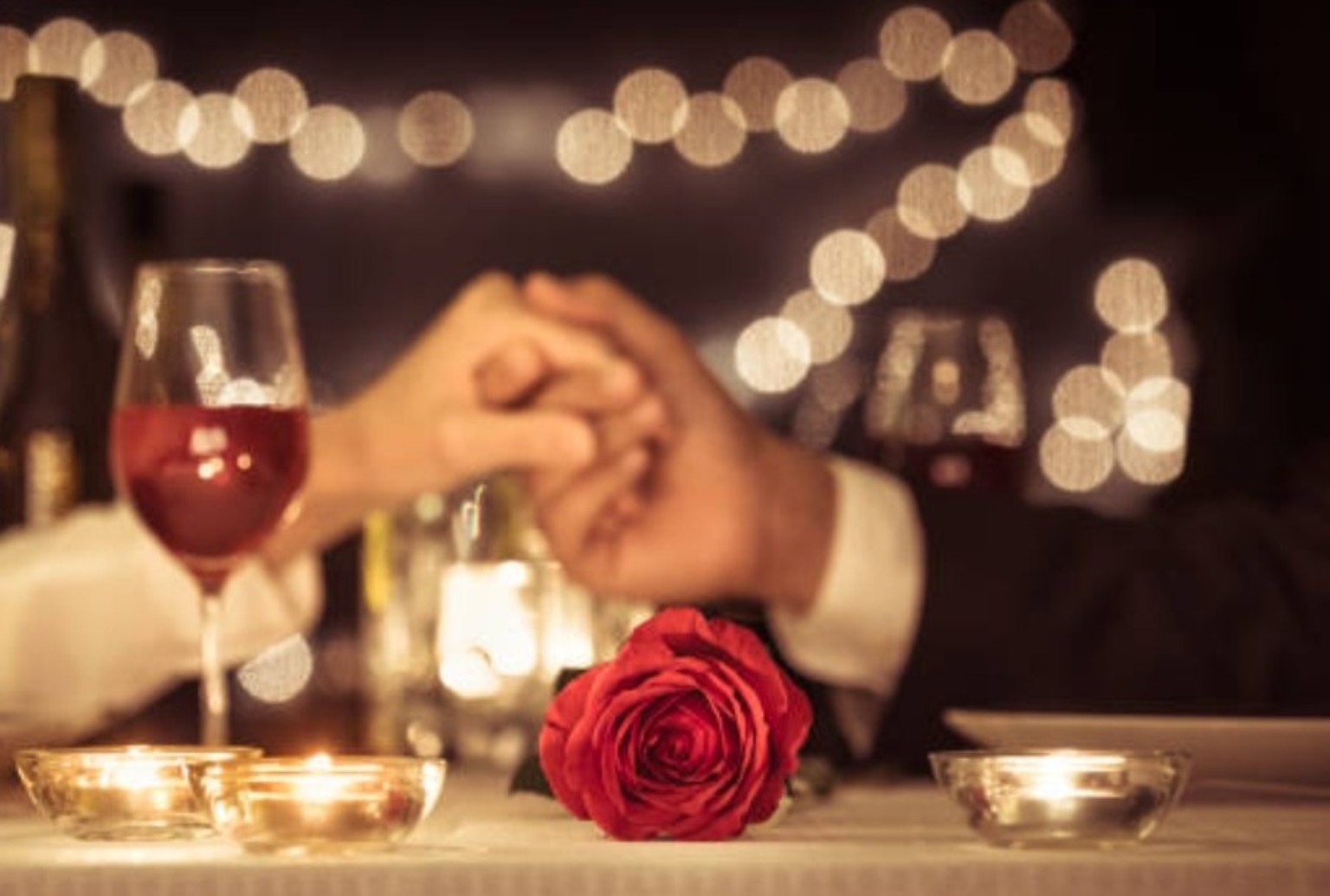 A couple holding hands during a romantic candlelit dinner